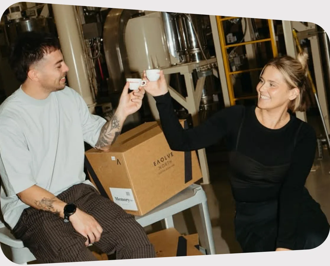 Two colleagues toasting with espresso cups in a roastery